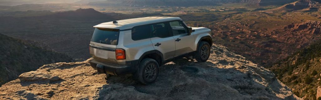 White Toyota suv parked on a rocky cliff overlooking a vast canyon landscape during sunset, highlighting off-road adventure capability.