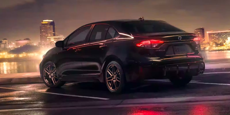 The side view of a 2024 Toyota Corolla driving on a highway at night in Kent, OH