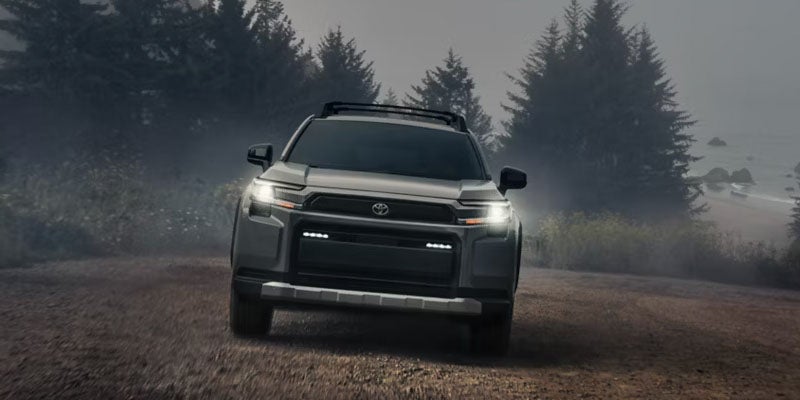 Toyota SUV driving on a forest trail in misty conditions.