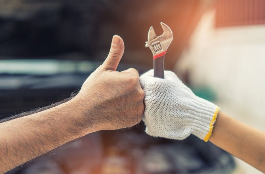 Mechanic holding a wrench while receiving a thumbs-up.